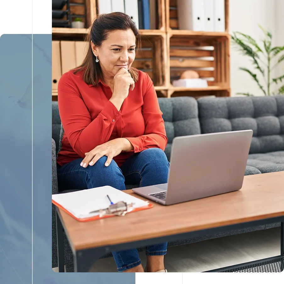 Woman working on laptop, thoughtful expression.
